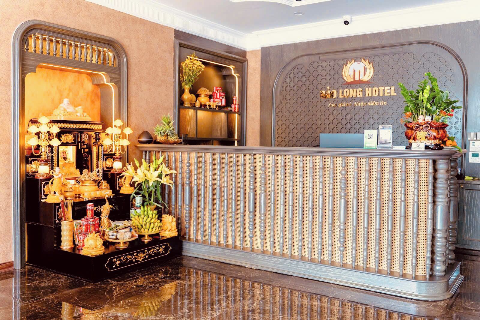 A reception desk with a decorative display of flowers and fruits, a sign for the Long Hotel, and a polished marble floor.