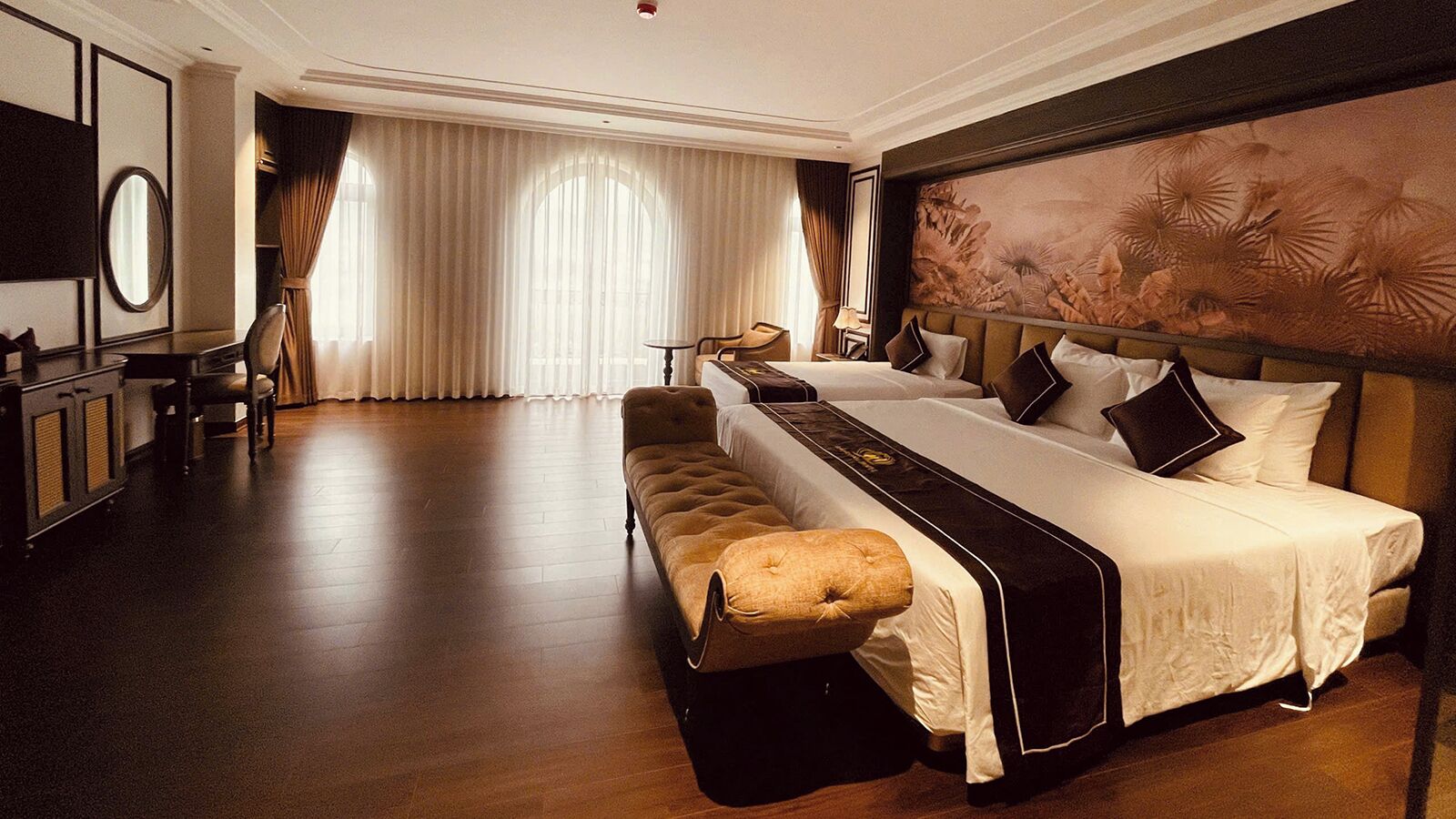 Una habitación de hotel con una cama grande, un banco, un escritorio y un espejo.