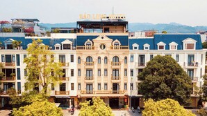 Un hotel con un cartel que dice 'BÁO LÔNG HOTEL' y un escaparate con la leyenda 'sweet coffee'.