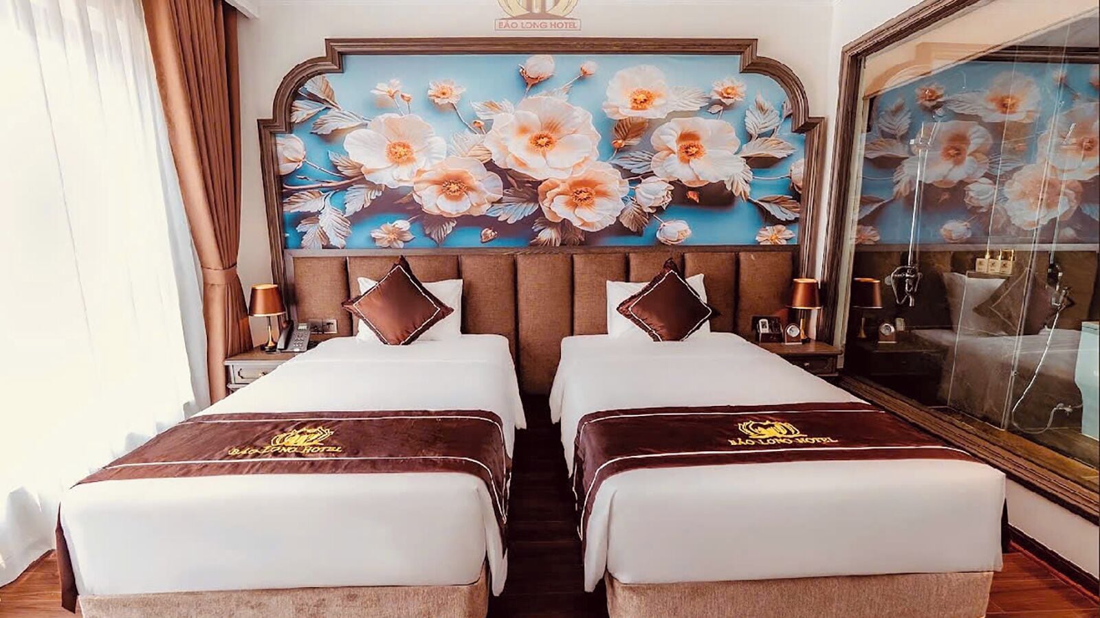 Une chambre d’hôtel avec deux lits, une grande œuvre d’art à motifs floraux accrochée au mur et un miroir.