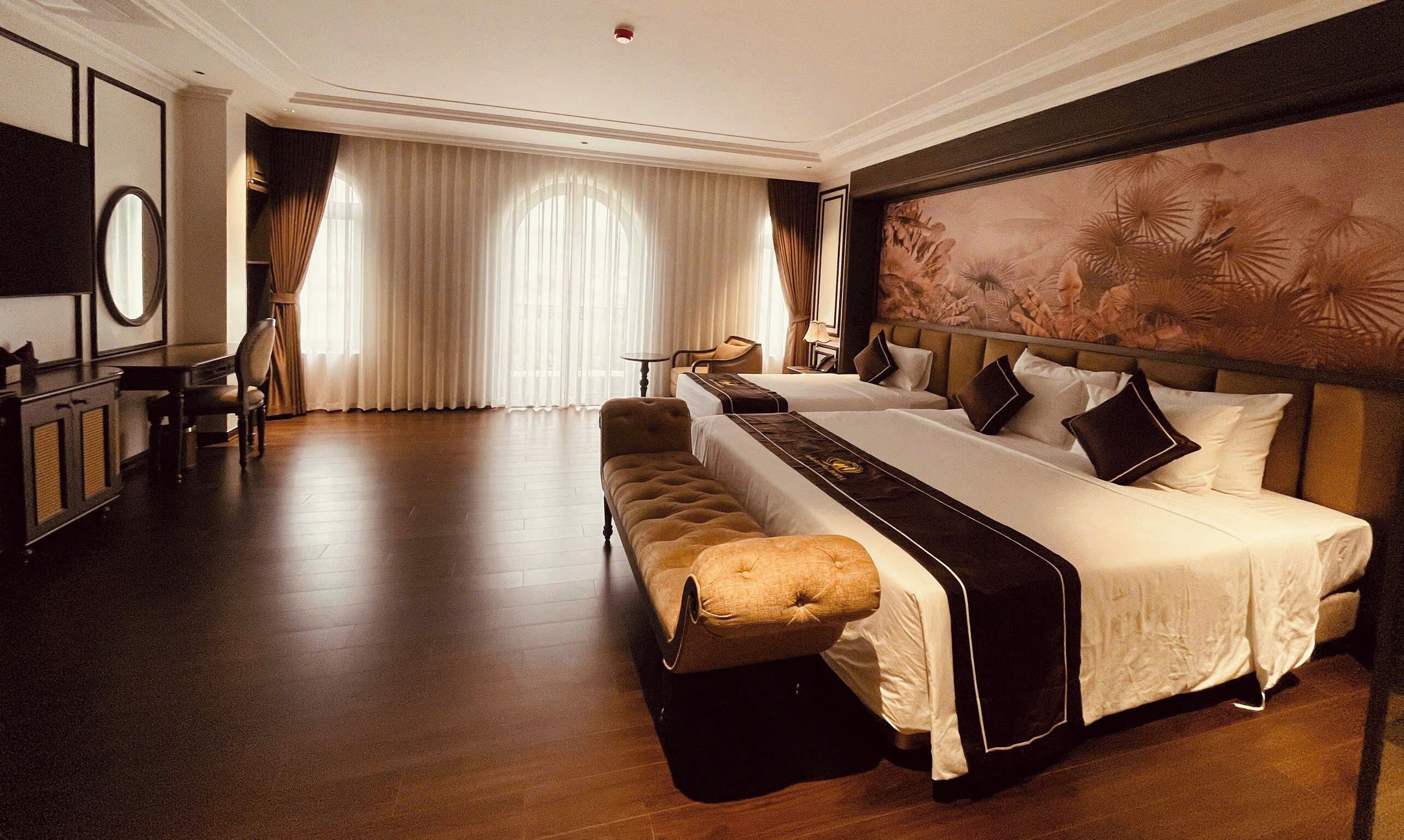 A hotel room with a large bed, a bench, a desk, and a chair.