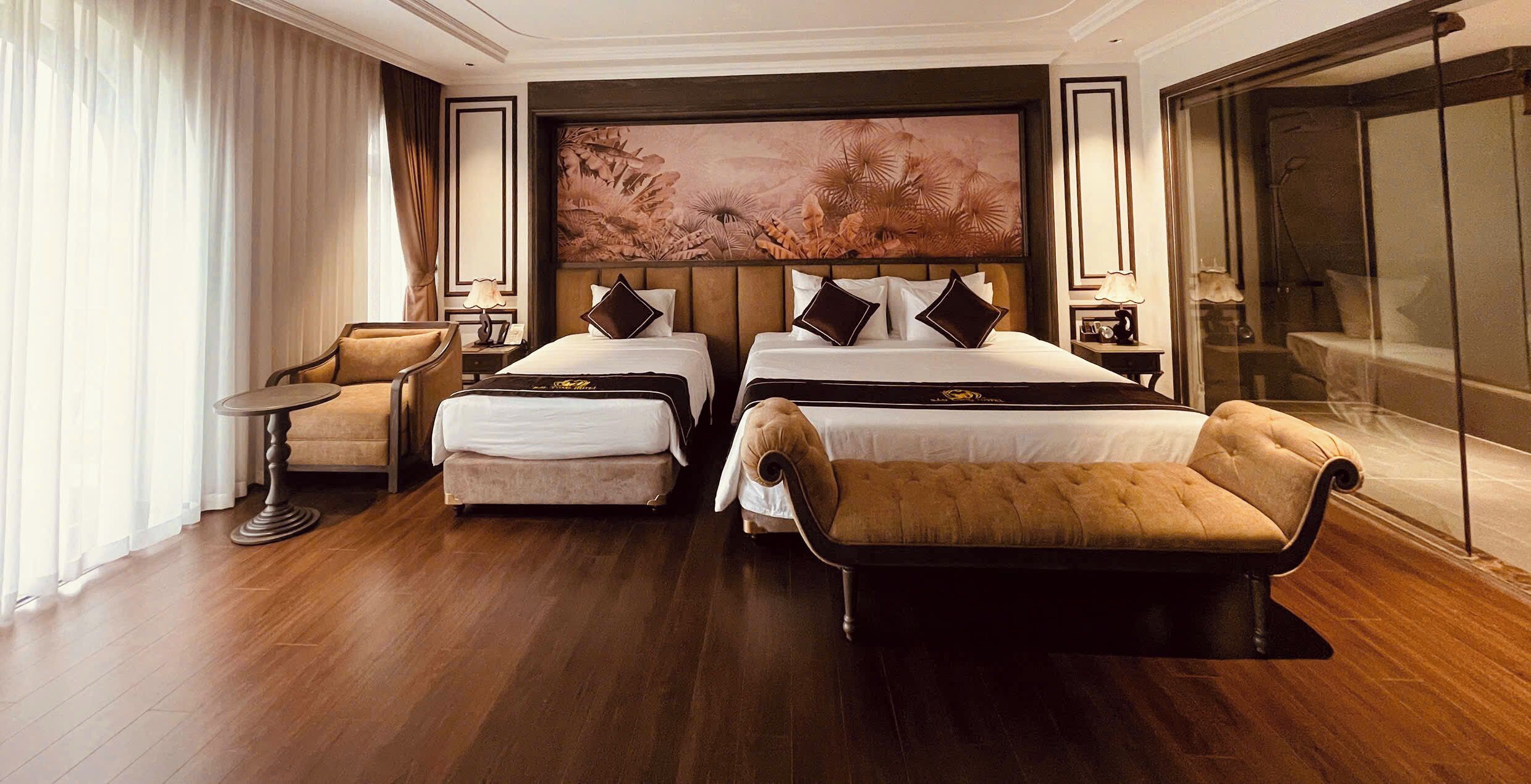 A hotel room with two beds, a sofa, a small table, and a large painting on the wall.