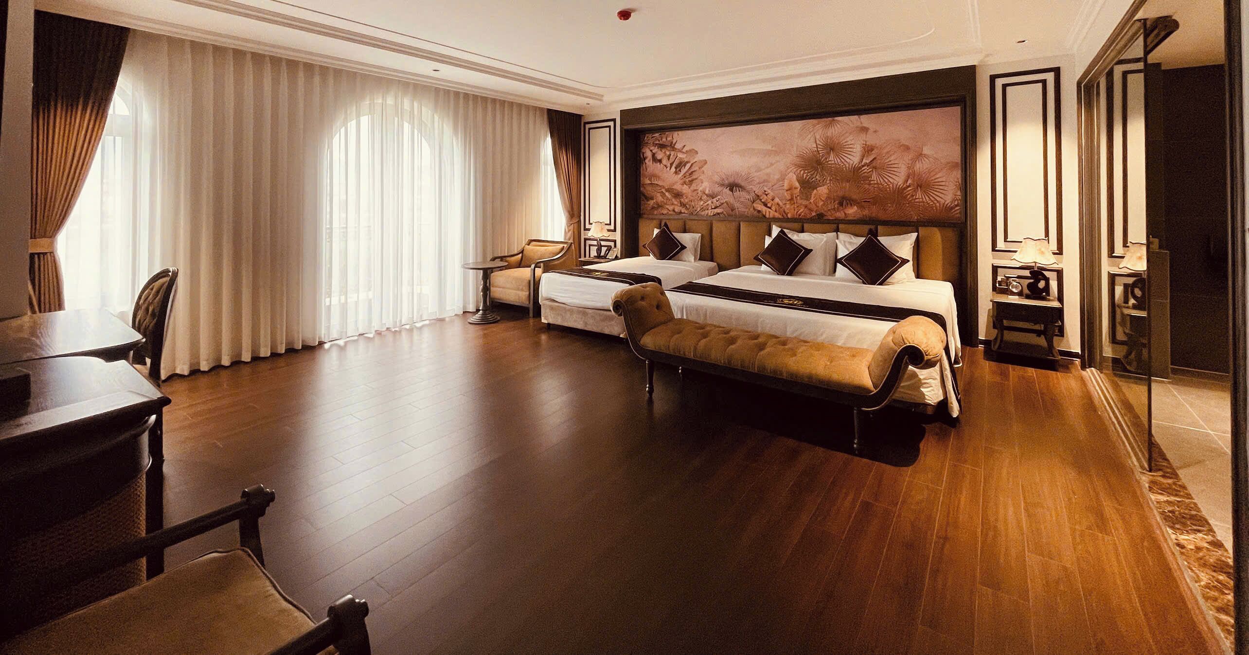 A hotel room with a large bed, a sofa, a desk, and a chair.