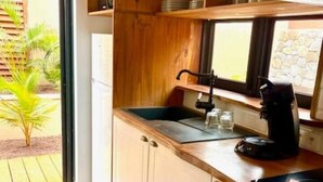 Eine Küche mit Holzausstattung, einer schwarzen Arbeitsplatte, einer Kaffeemaschine und einem Fenster mit Blick ins Grüne.