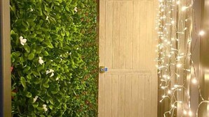 A wooden door with a green hedge on one side and string lights on the other. - Tiny house with private Jacuzzi (Saint-Paul)