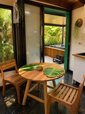 A round wooden table with two chairs, a woven basket, and a large green leaf decoration. - Tiny house with private Jacuzzi (Saint-Paul)