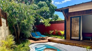 A backyard with a swimming pool, lounge chairs, and a wooden deck. - Tiny house boucan with pool (Saint-Paul)