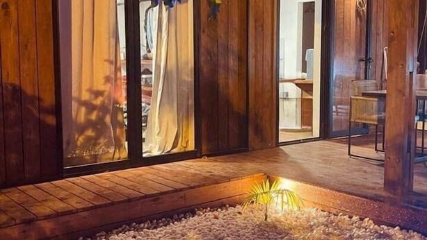 A wooden cabin with a pool, a covered patio, and a sliding glass door leading to an interior space. - Tiny house boucan with pool (Saint-Paul)