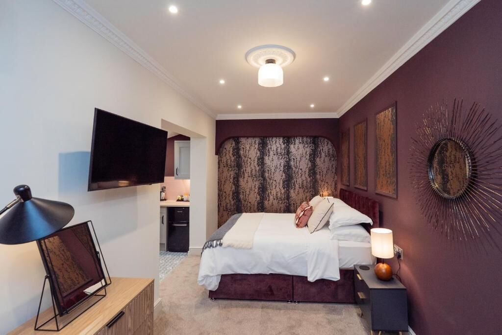 Une chambre à coucher comprenant un lit, une télévision, un bureau et un miroir fixé au mur.