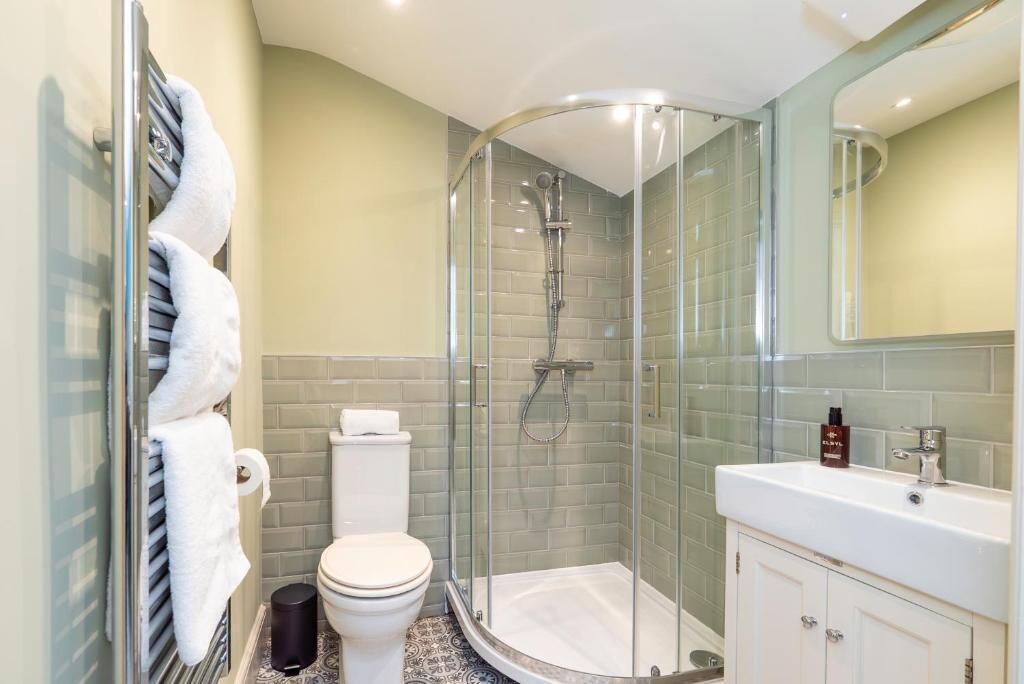 A modern bathroom with a glass-enclosed shower, a white toilet, and a white sink with a mirror above it.