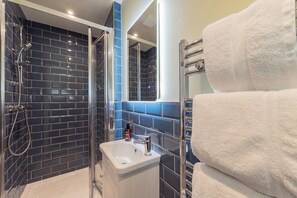 A bathroom with a glass-enclosed shower, a white sink, and a towel rack.