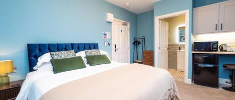 Un dormitorio con cama, mesita de noche y una zona de kitchenette.