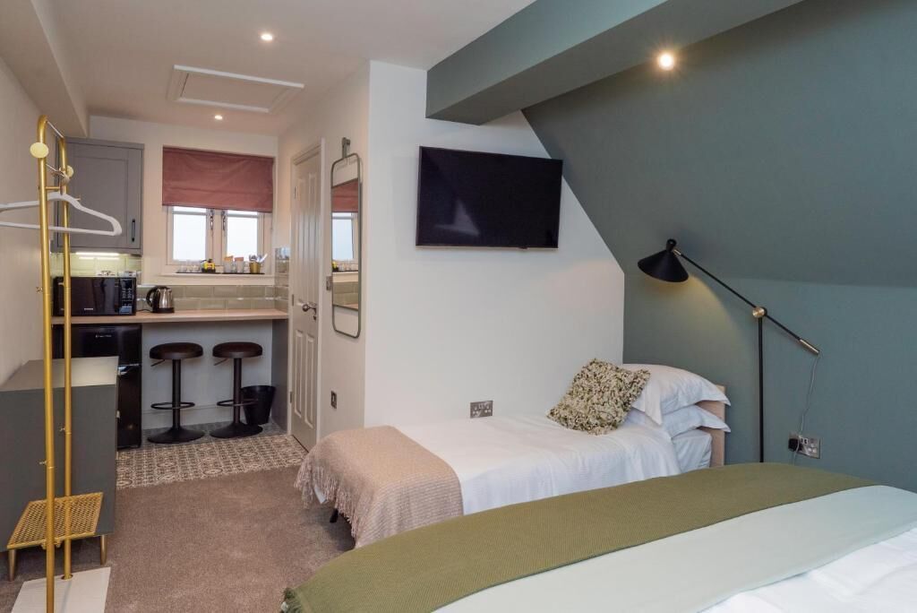 Un dormitorio con cama, mesita de noche y televisor montado en la pared.