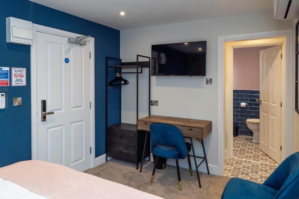Une pièce comprenant un lit, un bureau, une chaise, un téléviseur et une porte donnant sur une salle de bain.