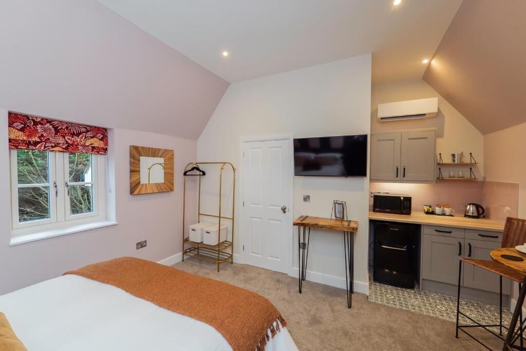 Un dormitorio con cama, una mesita de noche, una silla colgante y una ventana con cortinas.