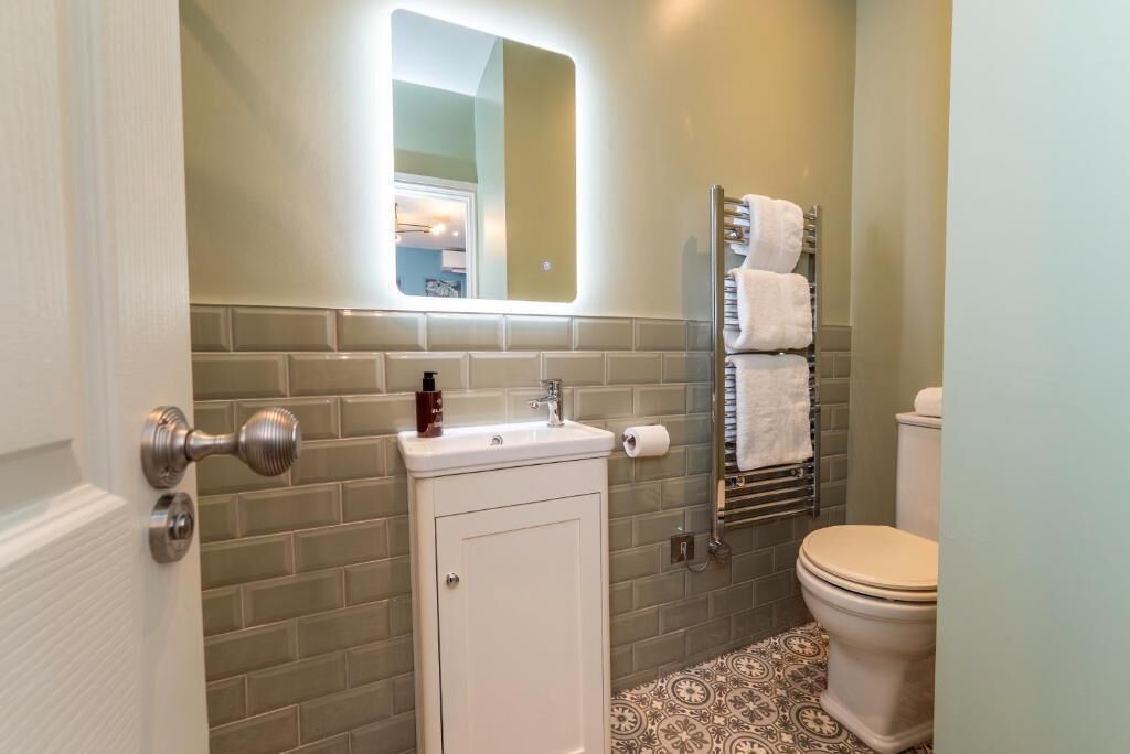 A bathroom with a white sink, a mirror, a towel rack, and a toilet.