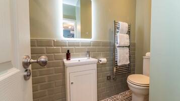 A bathroom with a white sink, a mirror, a towel rack, and a toilet.