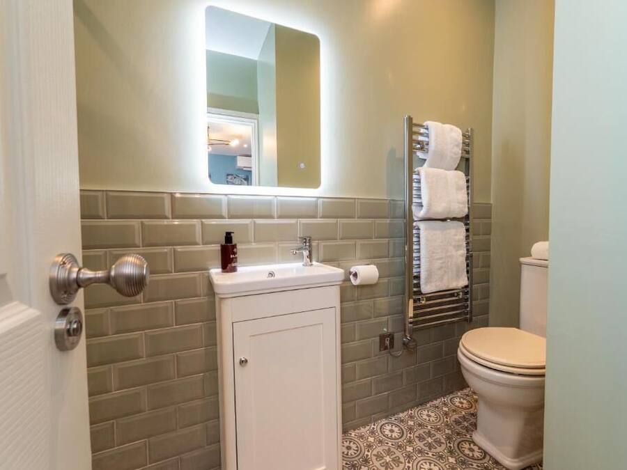 A bathroom with a white sink, a mirror, a towel rack, and a toilet.