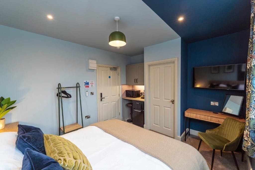 A bedroom with a bed, bedside table, and a desk with a chair.