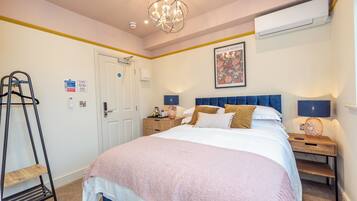 Une chambre à coucher comprenant un lit, des lampes de chevet, une table de chevet, une échelle, une porte et un appareil de climatisation.