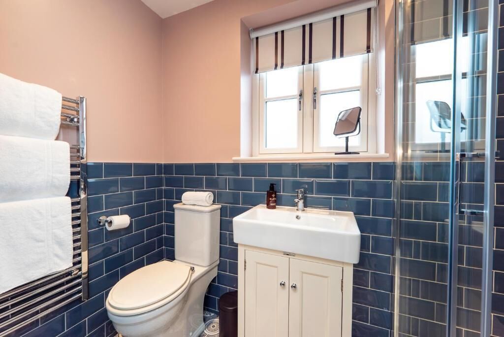 A bathroom with a toilet, a sink, a mirror, and a window.