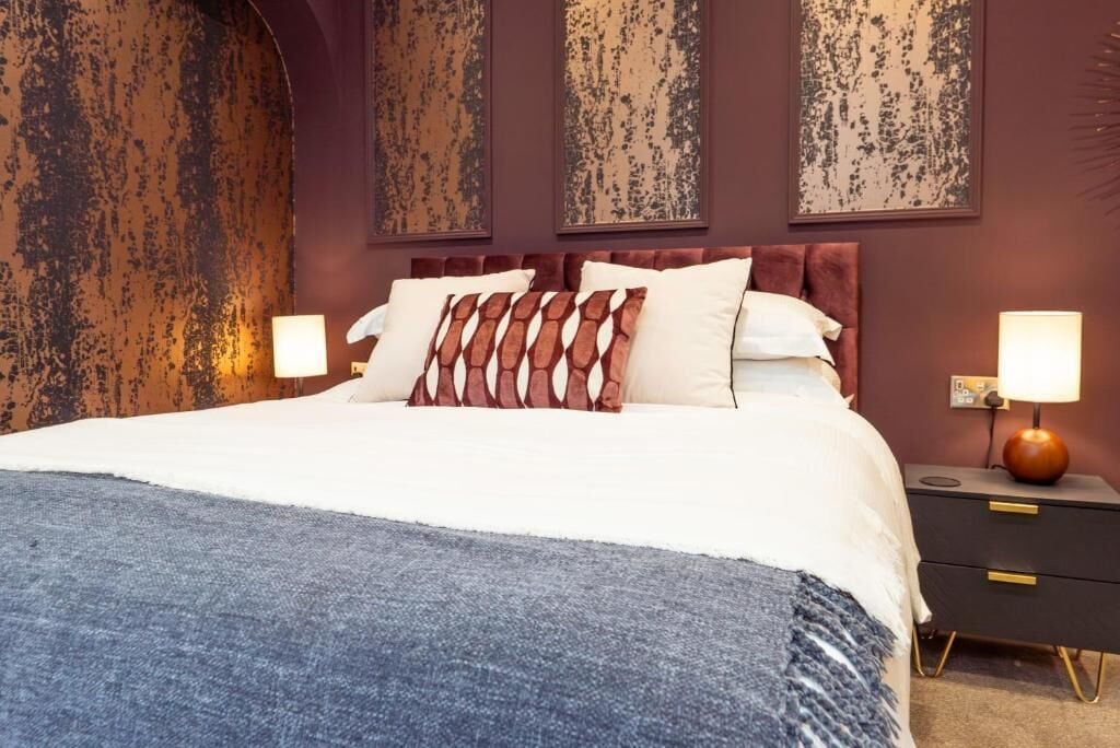 Ein Bett mit Kopfteil, zwei Nachttische und Wandbild.