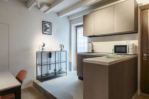 Une cuisine moderne dotée d’un four à micro-ondes encastré, d’un petit îlot central et d’une étagère.