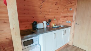A compact kitchen with wooden walls, a microwave, a toaster, and a sink. - Douglas (Stranraer)