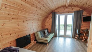 A cozy cabin with a curved wooden interior, a sofa, a TV, and a dining area. - Douglas (Stranraer)