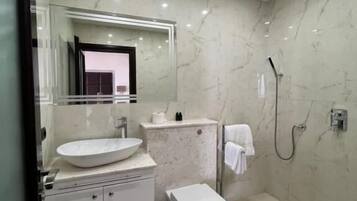 A modern bathroom with a large sink, toilet, and shower.