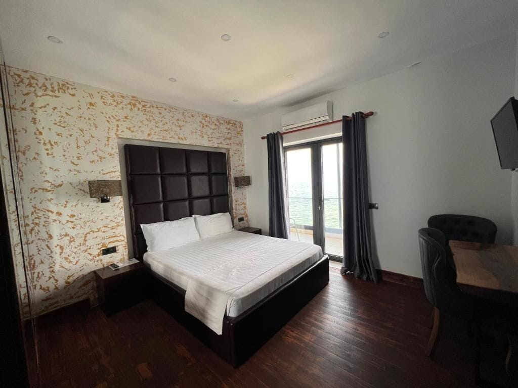 Habitación de hotel con una cama grande, un escritorio y vistas al mar.
