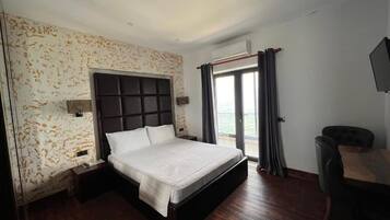 Habitación de hotel con una cama grande, un escritorio y vistas al mar.