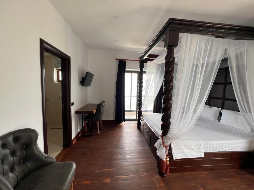 Un dormitorio con una cama con dosel, un escritorio, una silla y una televisión.