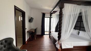 Un dormitorio con una cama con dosel, un escritorio, una silla y una televisión.