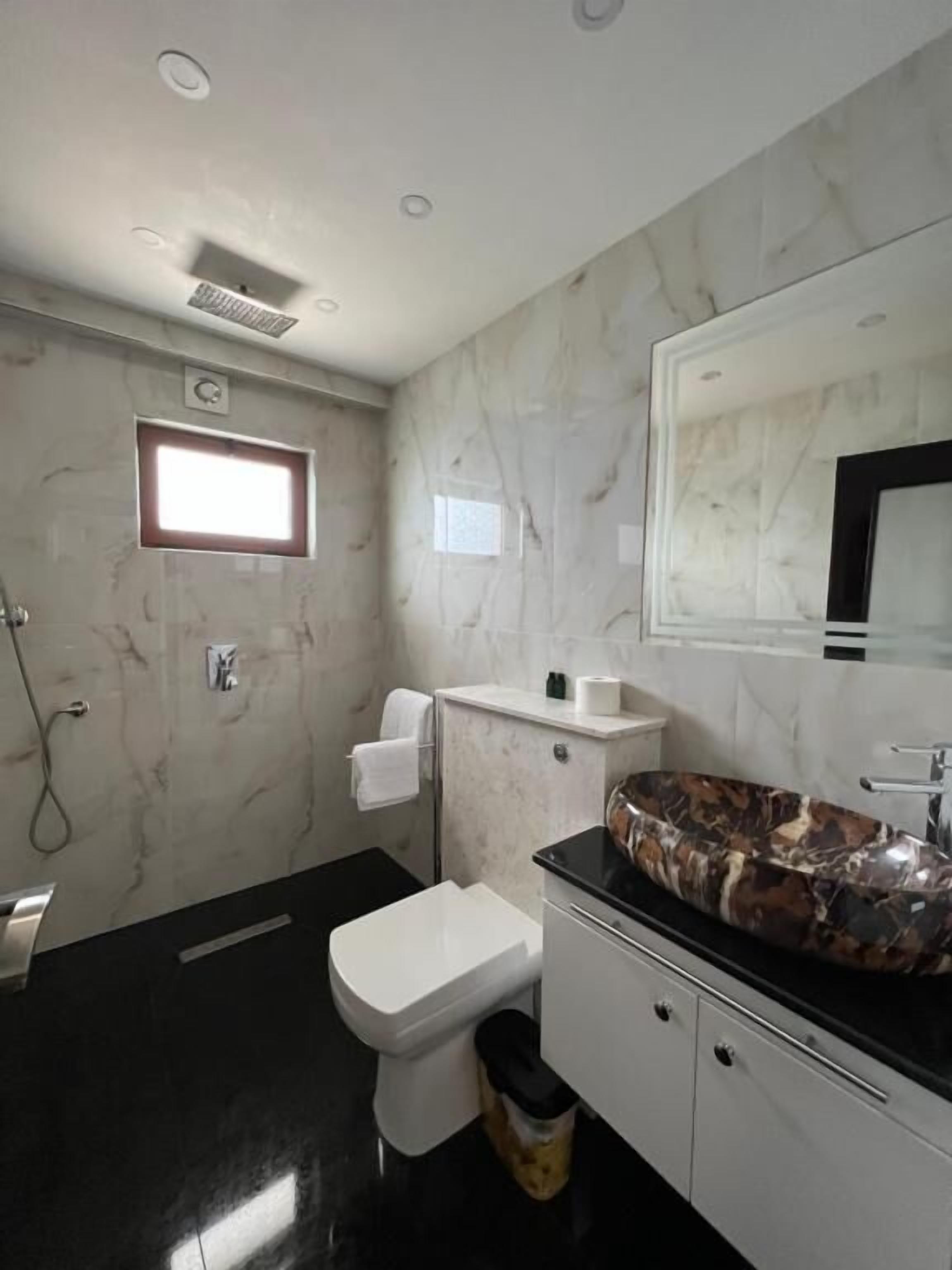 A modern bathroom with a toilet, sink, and mirror.