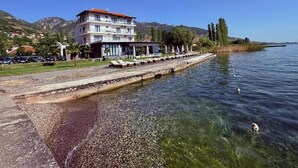 Un hôtel situé au bord de l’eau, offrant une vue dégagée sur le lac, doté d’un espace extérieur couvert avec des sièges et d’un parking.
