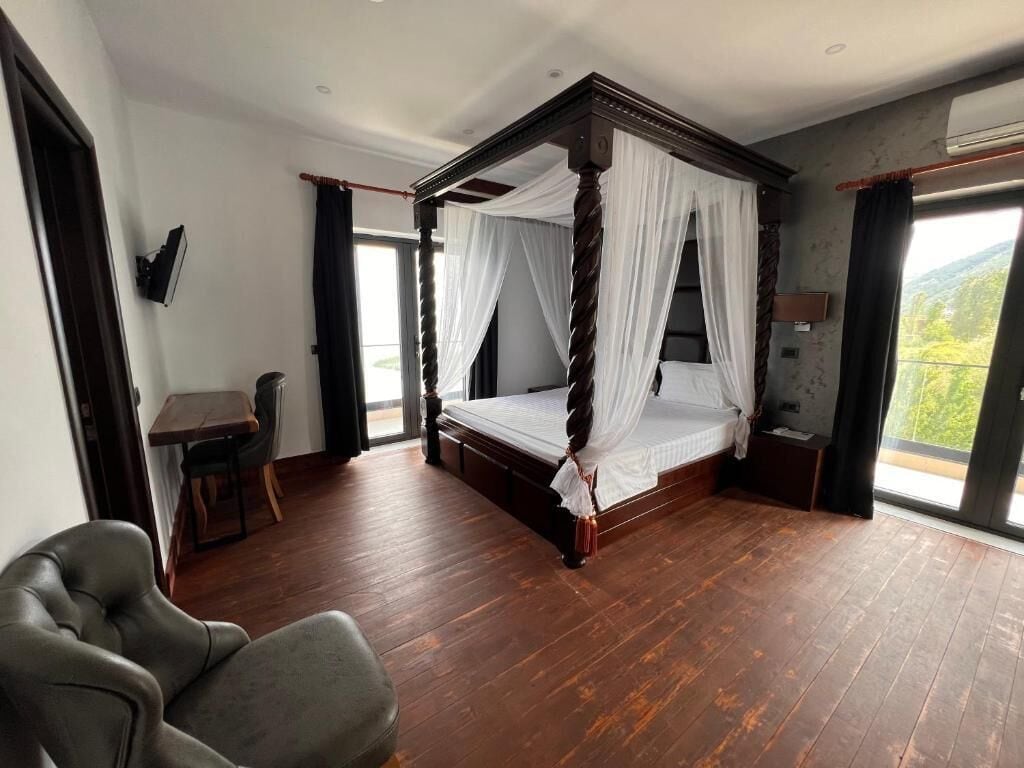 Una cama con dosel y cuatro columnas con vista al exterior.