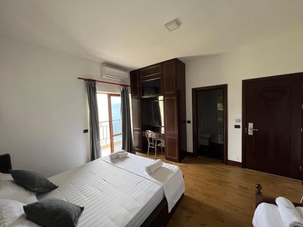 A hotel room with a bed, a desk, a chair, and a wardrobe.