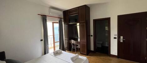 A hotel room with a bed, a desk, a chair, and a wardrobe.