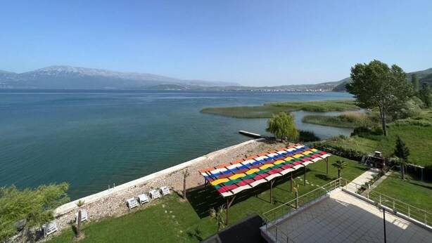 Une vue sur le lac, avec un espace patio aménagé, des chaises et un auvent coloré.