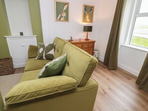 A living room with a sofa, a wooden side table, a lamp, and two framed pictures on the wall. - South Kirklauchline Farm (Stranraer)