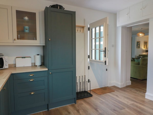 A kitchen with a teal cabinet, a microwave, a toaster, and a window with a view. - South Kirklauchline Farm (Stranraer)
