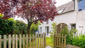A wooden gate, a tree with red leaves, and a white building with a window. - Gîte "Gite De La Rampotiere" with Private Terrace, Garden, and Wi-Fi (Quettreville-sur-Sienne)