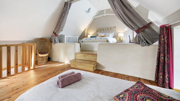A bedroom with a bed, a chair, a window, and a staircase. - Gîte "Gite De La Rampotiere" with Private Terrace, Garden, and Wi-Fi (Quettreville-sur-Sienne)