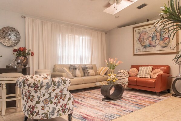 A living room with a sofa, armchair, coffee table, and a painting on the wall.
