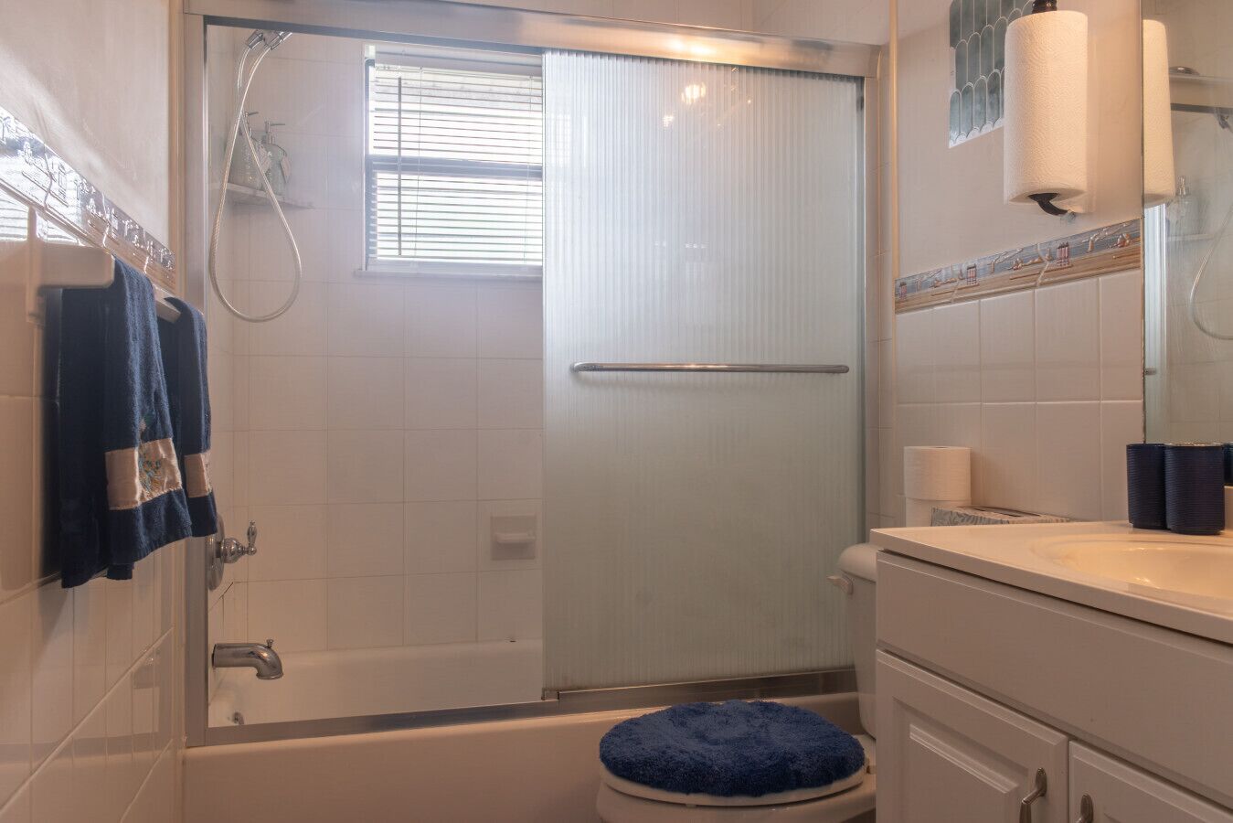 Une salle de bain avec une porte de douche en verre, des toilettes, un lavabo et un porte-serviettes.