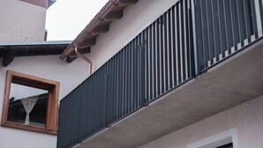 A building with a balcony, a window with a curtain, and a door. - Apartment 2 Casa Bepa - In the heart of Bormio, ideal for skiing and relaxation (Bormio)