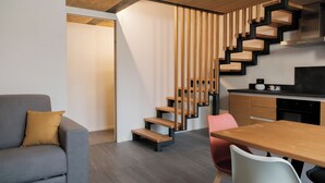 A modern interior with a grey sofa, a wooden staircase, a kitchen area, and a dining table. - Apartment 2 Casa Bepa - In the heart of Bormio, ideal for skiing and relaxation (Bormio)