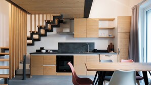 A modern kitchen with wooden cabinetry, a built-in stove, and a dining area with chairs. - Apartment 2 Casa Bepa - In the heart of Bormio, ideal for skiing and relaxation (Bormio)