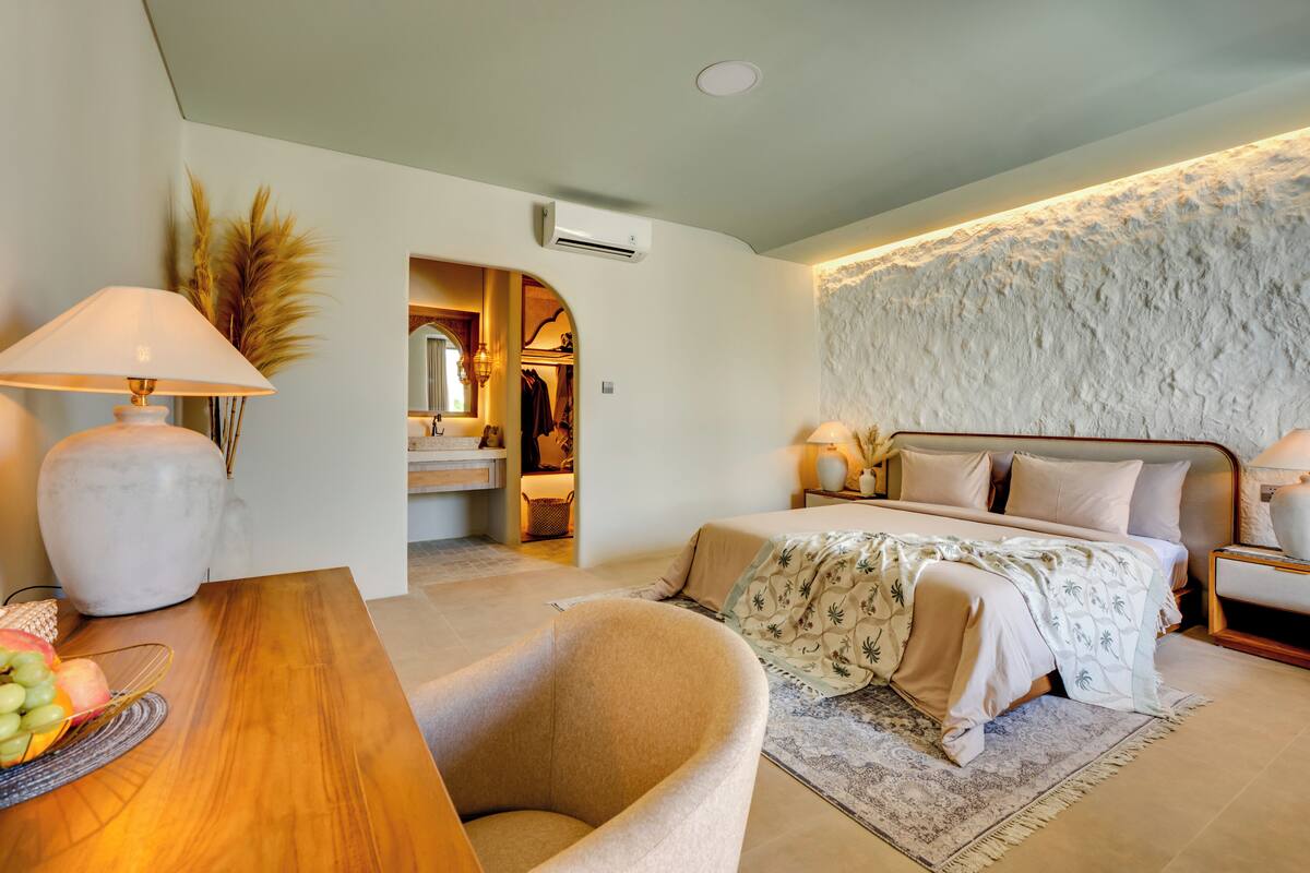 A bedroom with a bed, bedside tables, a desk with a lamp, and a chair.